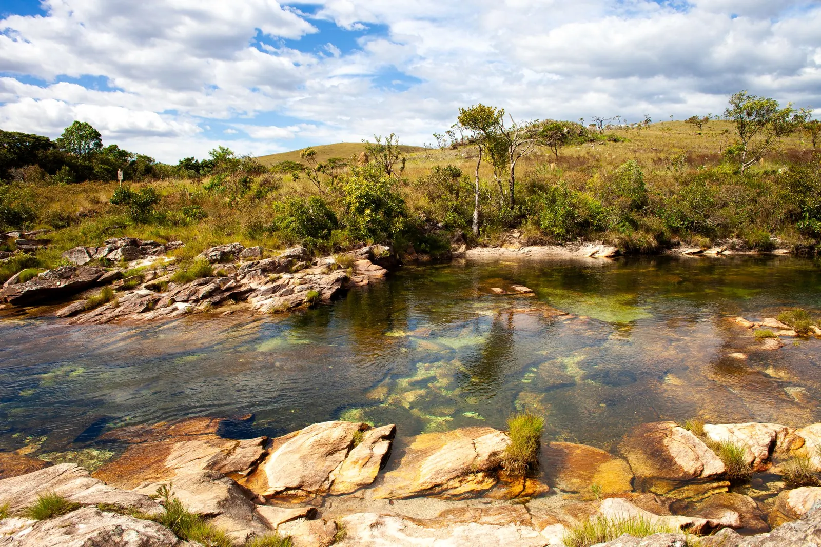 Rio de águas claras entre pedras e vegetação de cerrado