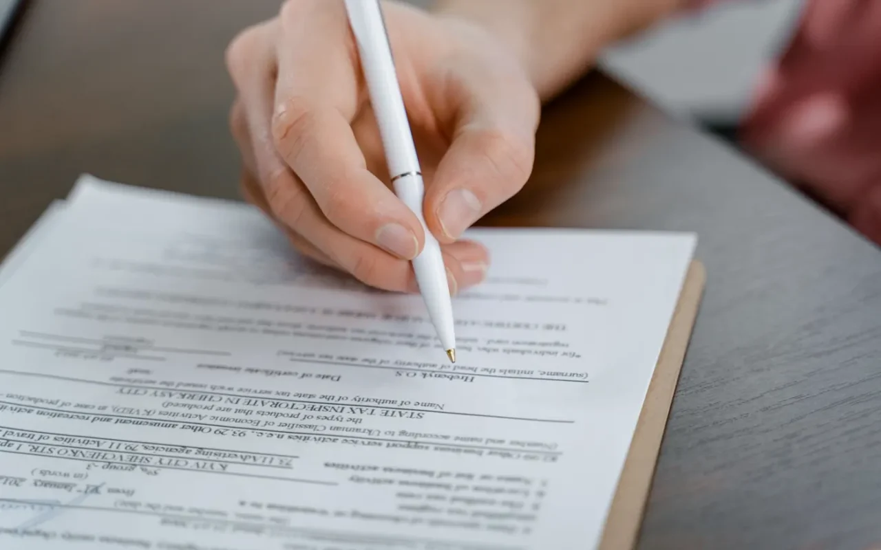 Pessoa assinando um documento sobre a mesa