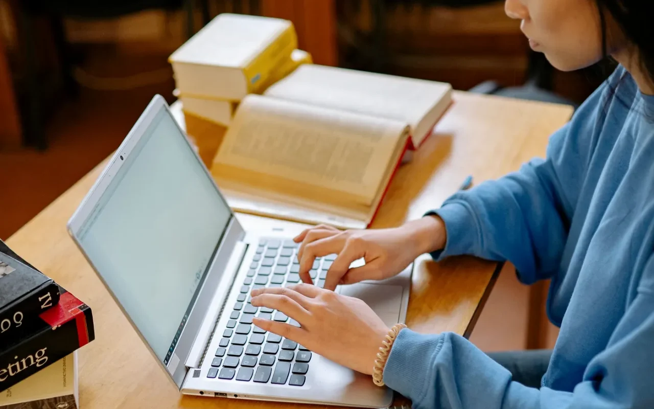 Estudante com livros e computador, preparando-se para provas